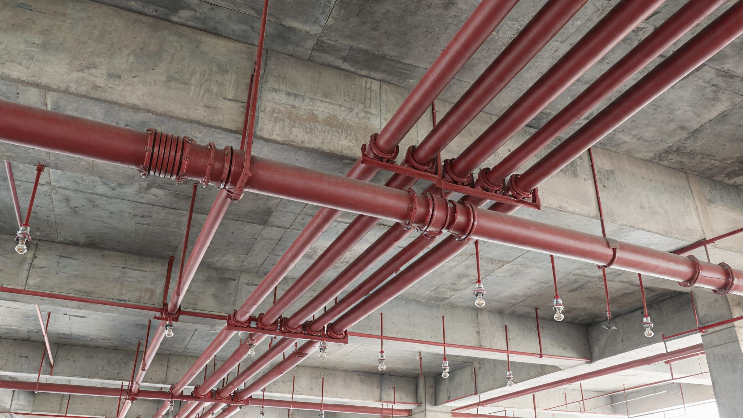 Beton tavan altında kırmızı sprinkler boru hatları ve sprinkler başlıkları